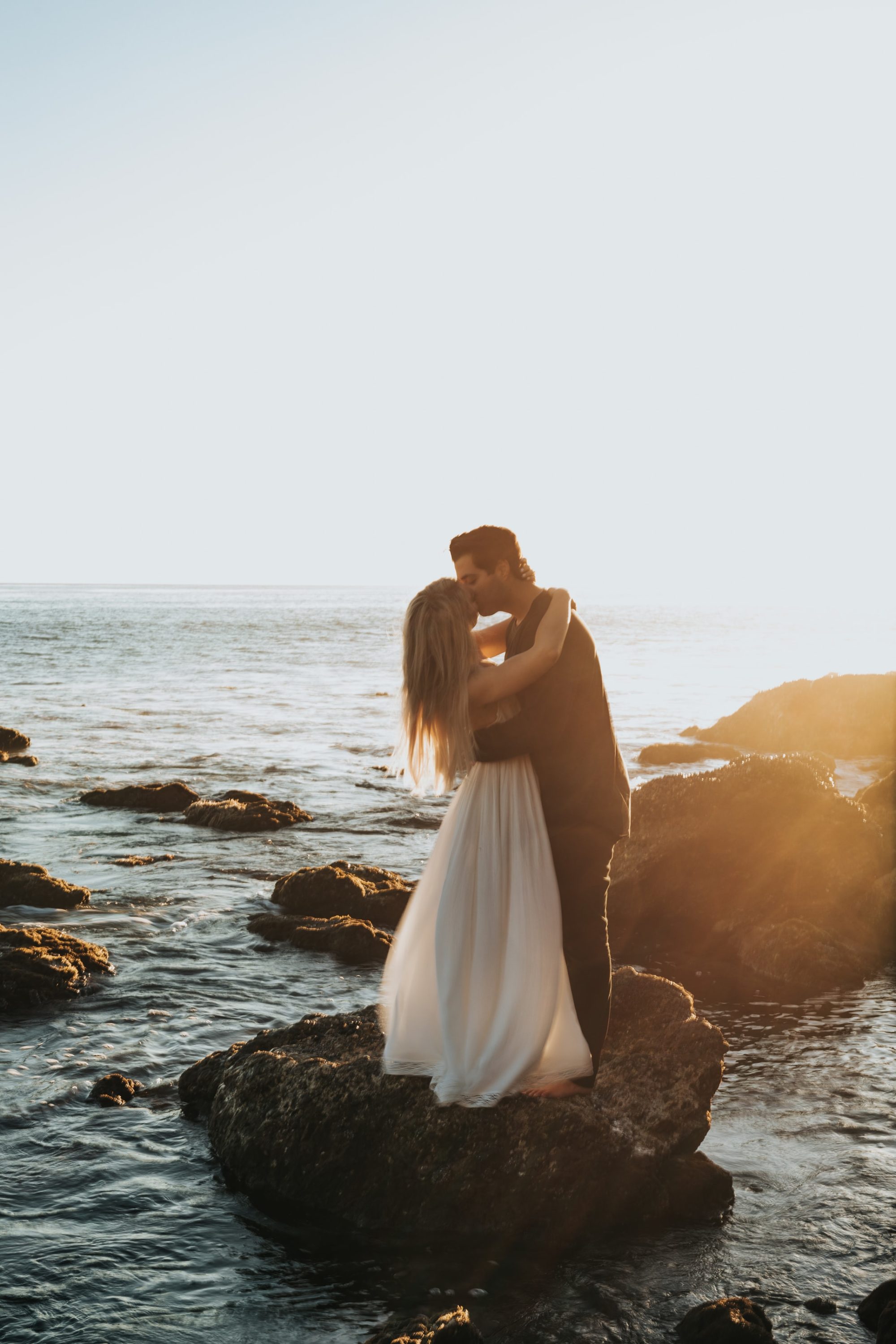Young cute couple honeymoon sit on rocks posing and holding their hands on  dating in a beautiful place italy near ocean and mountains, hug, smile and  talk to each other Stock Photo |